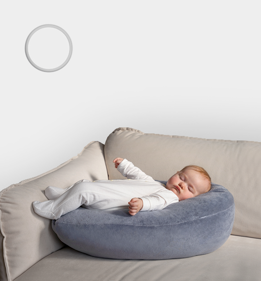 Frameless round gypsum air diffuser RONDO installed in a white ceiling above a sleeping baby to demonstrate quiet, draft-free performance.